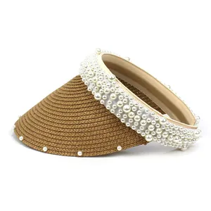 Detail of brown straw sun hat featuring elegant pearl trim and woven texture