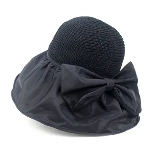 Detail of wide-brimmed black sun hat featuring elegant bow and straw patchwork design