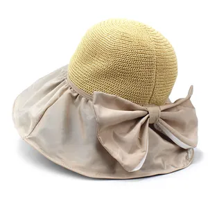 Detail of wide brim sun hat featuring woven straw texture and large silk bow decoration