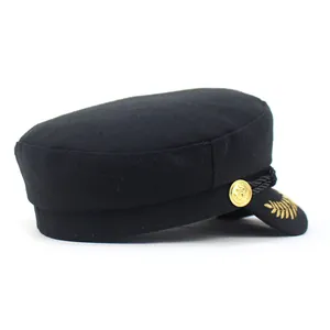 Detail of black wool sailor cap featuring golden anchor button and embroidery