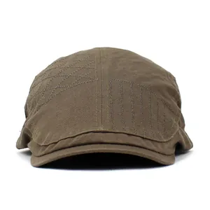 Macro detail of military green cotton newsboy cap featuring geometric stitch patterns