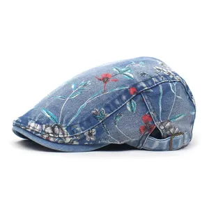Blue denim beret hat with red floral print and adjustable metal buckle on white background