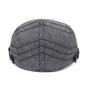 Detailed view of grey plaid beret hat with adjustable side strap and metal buckle