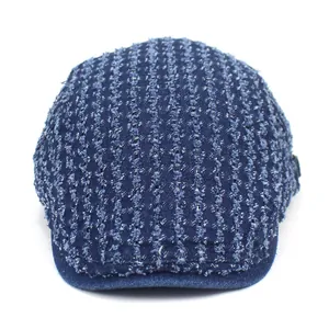 Detail of distressed dark blue denim ivy cap featuring vertical frayed stripe textures