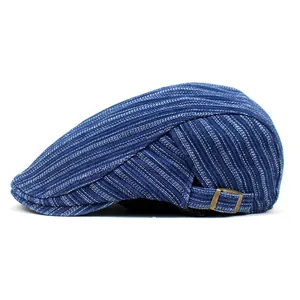 Detail of blue striped denim flat cap showing the metal buckle and fabric texture