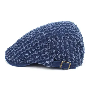 Close-up of distressed denim beret featuring frayed texture and brass adjustment buckle