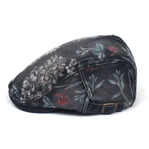 Detail view of washed denim flat cap featuring vintage floral patterns and metal buckle