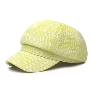 Fashionable newsboy cap for women in yellow and white tweed fabric on white background