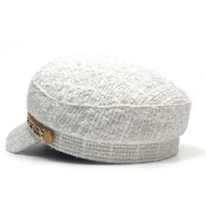 Detail view of white tweed newsboy cap with textured fabric and gold chain accent