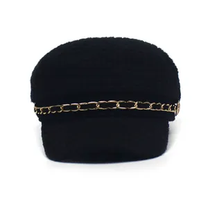 Detailed texture of black tweed newsboy hat with a decorative gold metal chain link