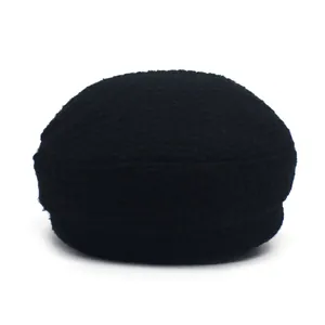Close-up of the woven wool texture and brim detail of a black tweed baker boy cap