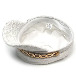 Detailed view of white tweed baker boy hat with internal label showing size 58 and gold chain