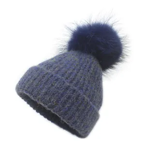 Detail of navy chunky knit beanie with mixed texture and fluffy pom-pom top