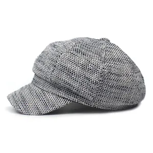 Close-up of textured black and white newsboy cap showing detailed woven tweed fabric