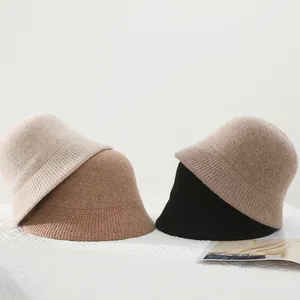 Nahaufnahme gestapelter Strick-Fischerhüte aus Wollmischung in Beige, Camel und Schwarz