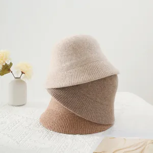 Drei Strick-Anglerhüte in Creme, Hellbraun und Camel mit Ripp-Design auf weißem Stoff