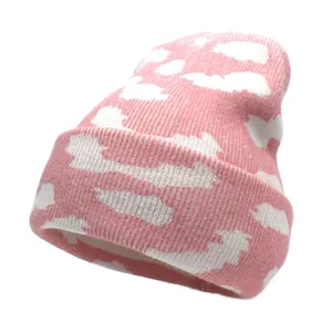 Gros plan détaillé du bonnet en maille rose avec motifs nuages blancs et bord replié