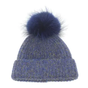 Close-up of thick navy blue ribbed knit beanie featuring a large matching fluffy pom-pom