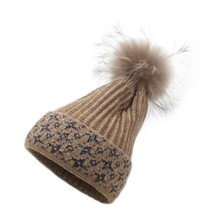 Women's khaki knit beanie with fluffy fur pom-pom and silver glitter star patterns