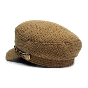 Close-up of brown plaid wool baker boy hat with gold chain and embossed metal button