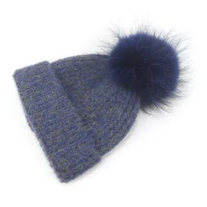 Close-up of thick ribbed knit texture and fluffy faux fur pompom on navy winter beanie