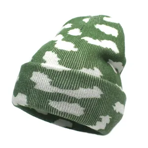 Gros plan du bonnet en tricot vert et blanc avec motif nuage et texture côtelée
