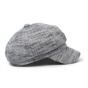 Detailed close-up of grey tweed newsboy cap fabric texture and top button design