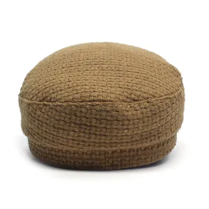 Close-up of the coarse weave texture and cross-stitch pattern on the brown wool baker boy hat