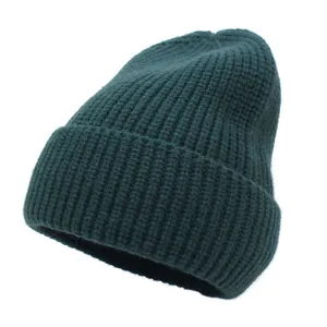 Close-up of dark green beanie showing thick knitted texture and minimalist folded cuff