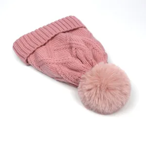Close-up of pink cable knit beanie featuring a soft texture and a fluffy pom-pom detail