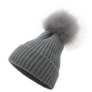 Détail d'un bonnet en maille grise avec pompon duveteux et texture à rayures épaisses