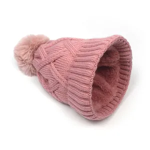 Detail of pink knitted beanie with soft faux fur pom-pom and thick warm fleece lining