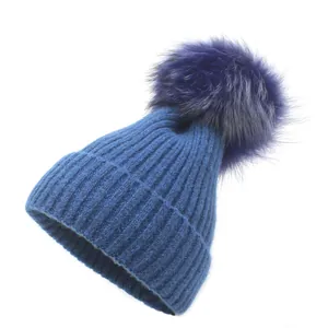 Vue détaillée du bonnet en maille côtelée bleu foncé avec un gros pompon en fourrure