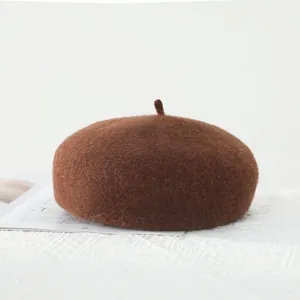 Close-up of a vintage brown wool beret with small tail detail on white tablecloth