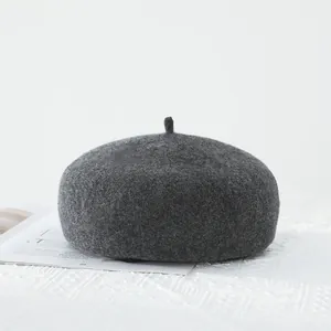 Close-up of charcoal grey wool beret with soft textured finish on white lace fabric