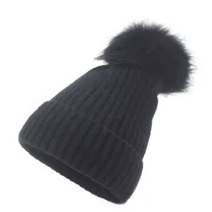 Détail d'un bonnet en tricot côtelé noir avec un grand pompon en fausse fourrure douce
