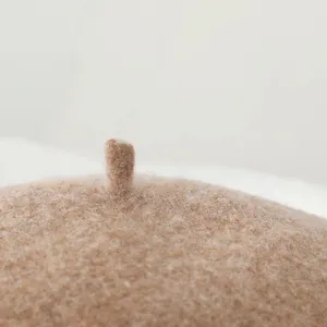 Close-up of the small top detail and wool texture on a brown beret hat for women