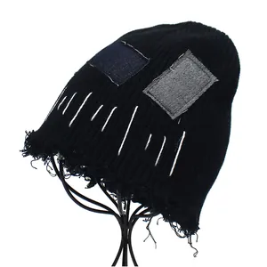 Detail of distressed black knit beanie with vintage patches and raw fringe edges