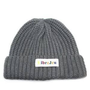 Dettaglio del berretto in maglia grigia con etichetta colorata LibreJeu sul risvolto