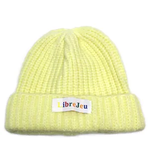 Dettaglio del berretto in maglia a coste giallo chiaro con etichetta colorata LibreJeu