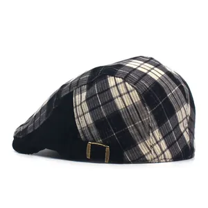 Detail view of plaid newsboy cap with bronze metal buckle and corduroy side panel