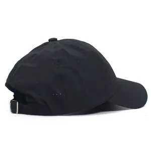 Detail of black quick-dry golf cap showing breathable mesh holes and metal buckle