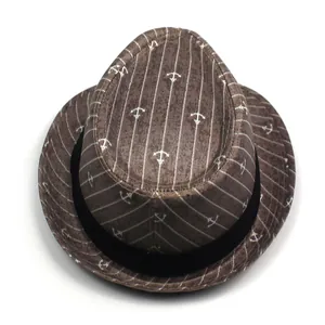 Detail view of brown fedora with anchor pattern and black fabric band on white background
