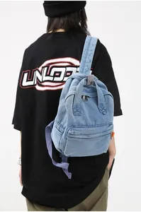 Detailansicht des blauen Denim-Rucksacks mit lila gewebten Riemen am weiblichen Modell