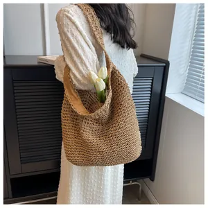 Dettaglio borsa a tracolla in paglia intrecciata, grande borsa secchiello per l'estate.