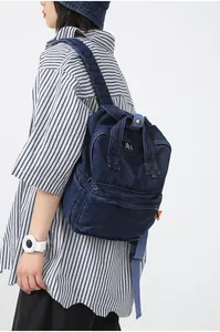Detail eines dunkelblauen Denim-Rucksacks mit Metall-Reißverschlüssen am Model