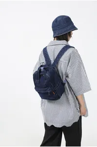 Detailansicht des dunkelblauen Denim-Rucksacks mit Reißverschlusstasche und Textur