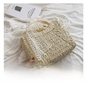 Detailed texture of hand-woven straw beach bag with wooden handle and lace bow accent