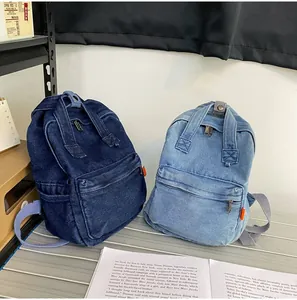 Detailansicht dunkel- und hellblauer Denim-Rucksäcke auf einem Schreibtisch mit Büchern