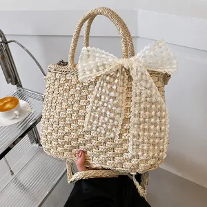 Détail d'un sac à main en paille avec nœud en dentelle délicate et broderies florales